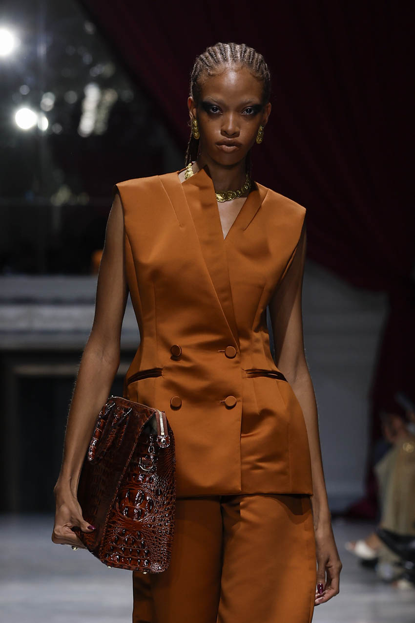 Model wearing an orange suit with a dark background